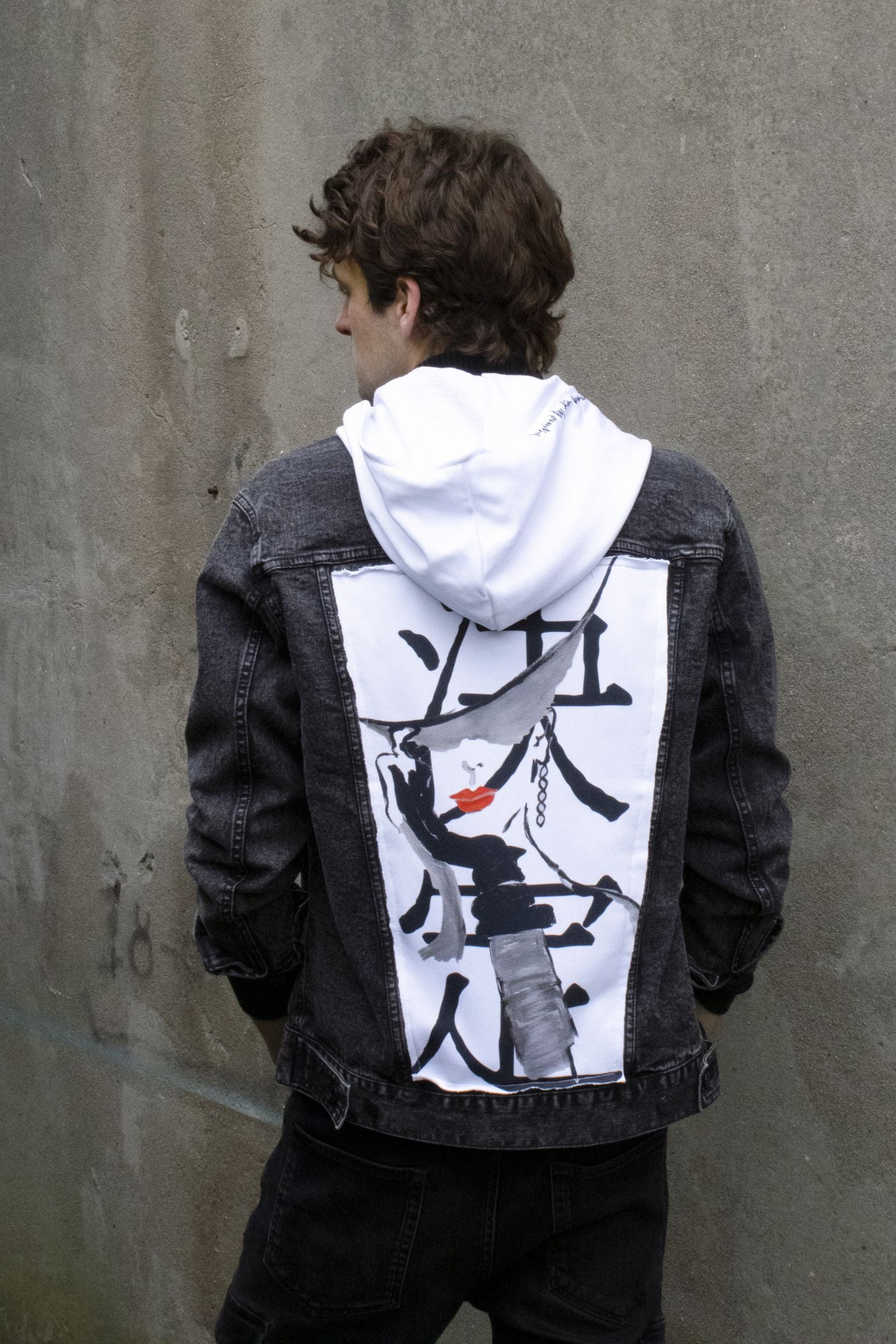 backside of the grace jacket. Black denim fabric with white panels and hood