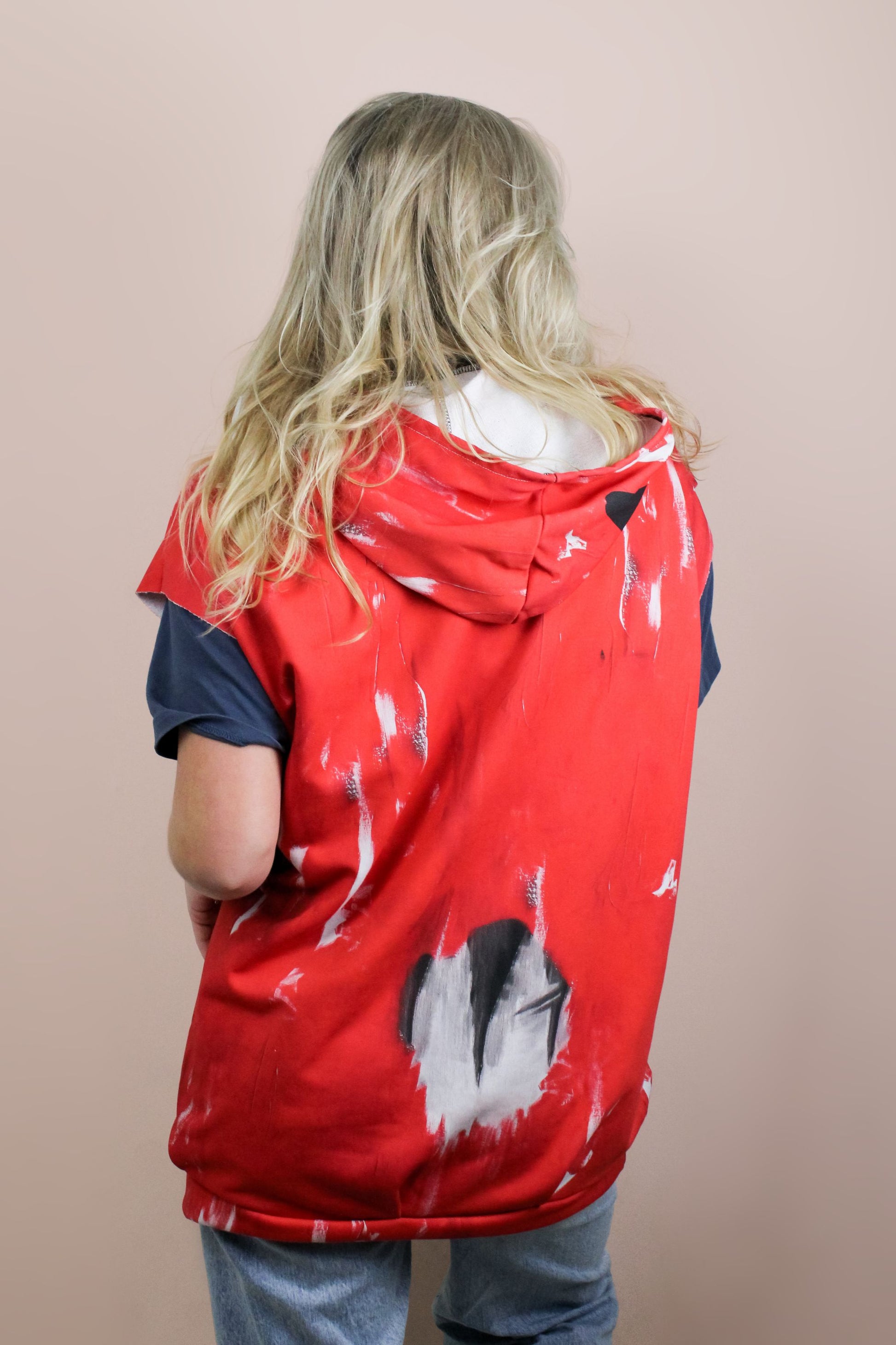 back view of sleeveless red hoodie with raw finish at armholes