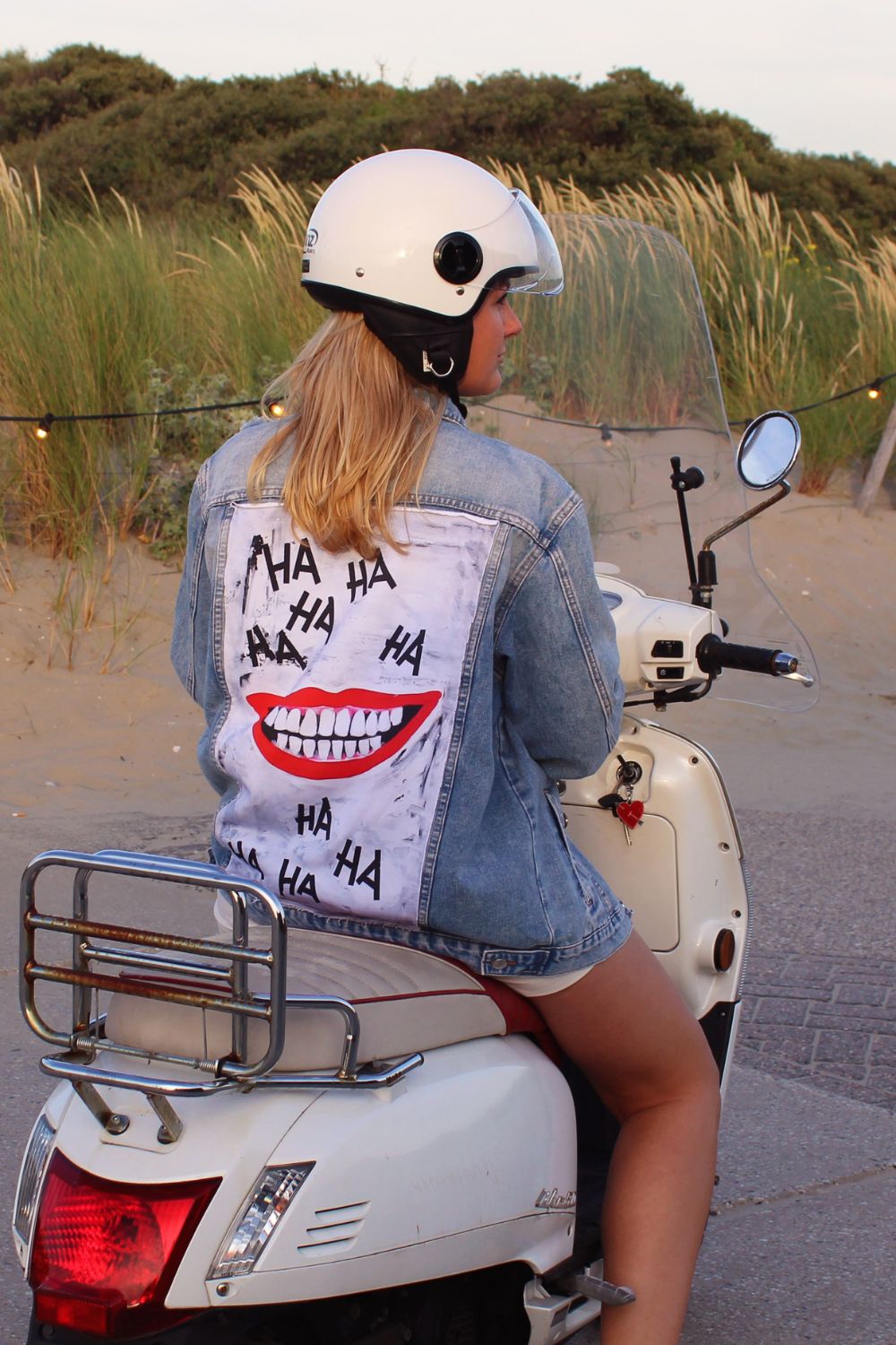 A unique denim jacket with a smiling face lauging on a panel on the backside