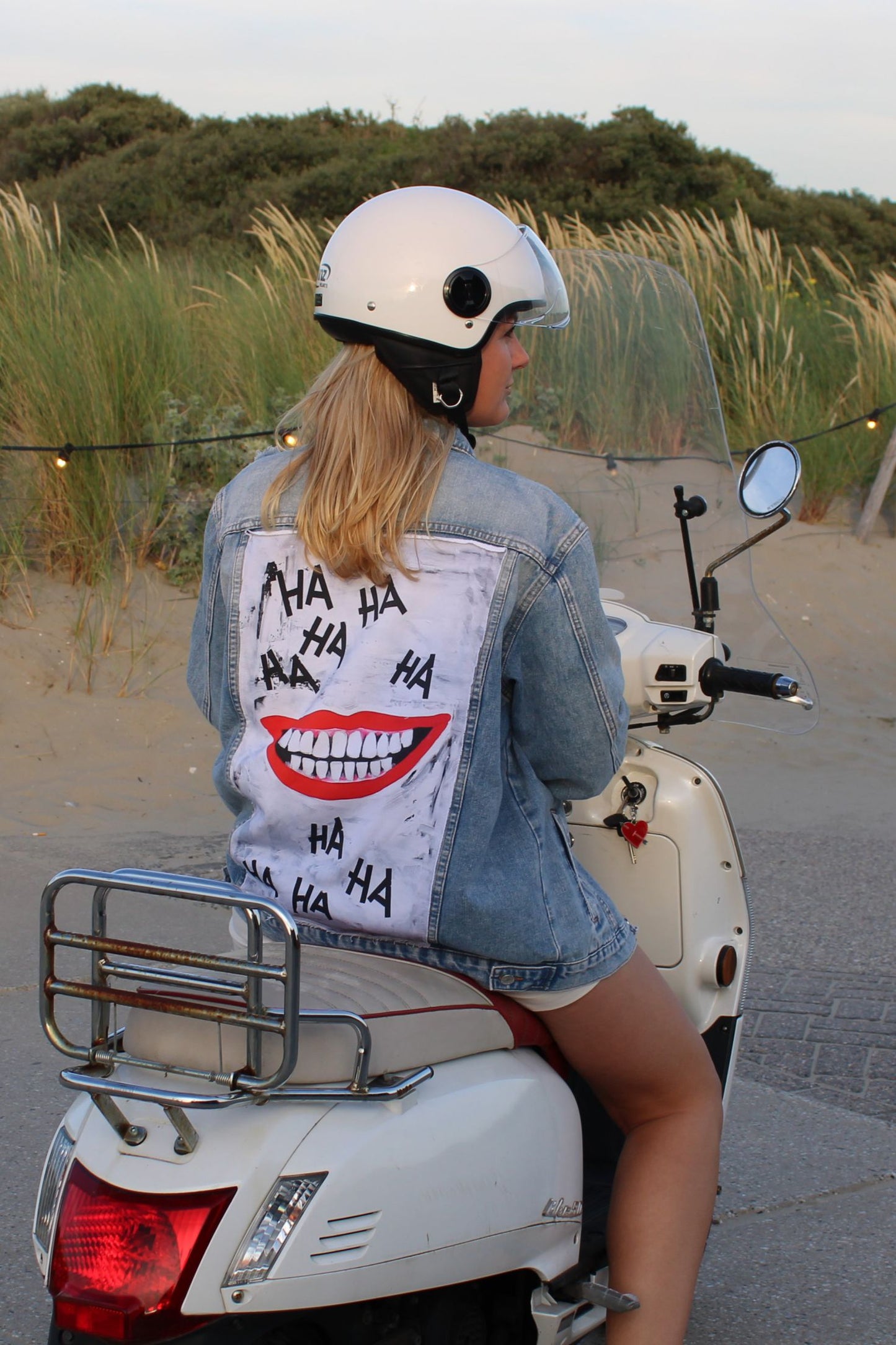 A unique denim jacket with a smiling face lauging on a panel on the backside