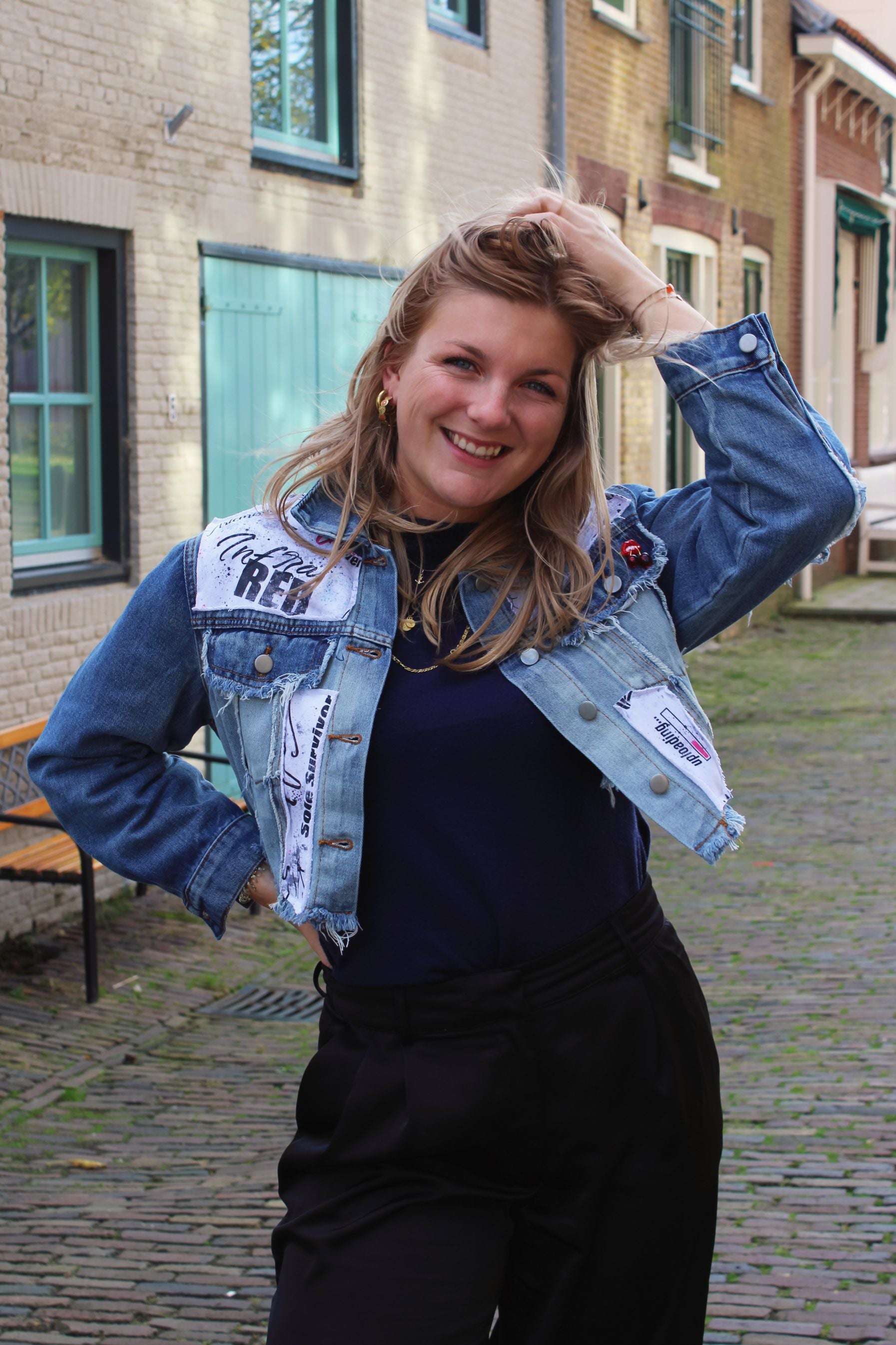 Cropped light blue denim jacket with raw edge design and stitched-on text panels for a bold street-style look.