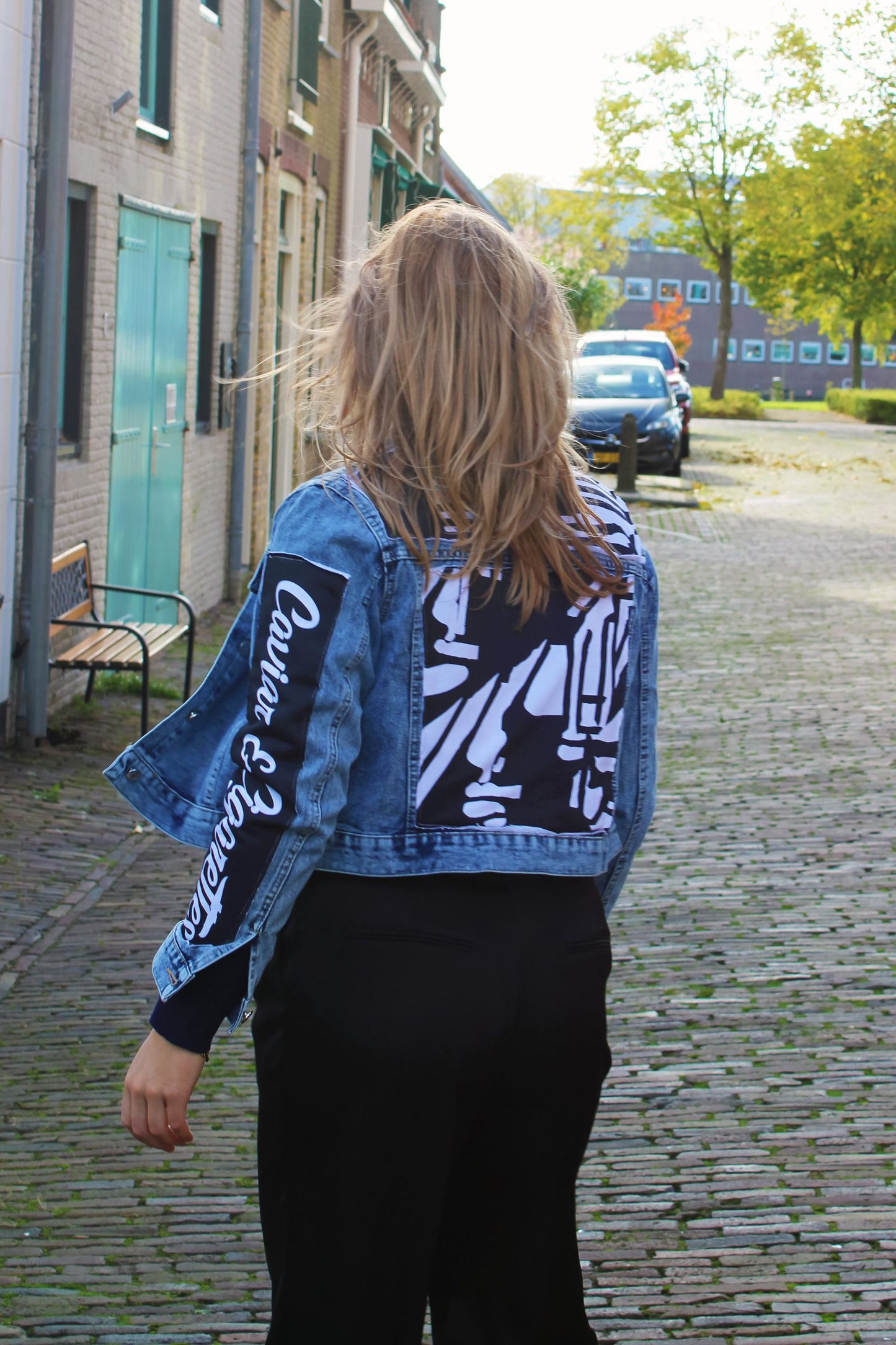 Model wearing a light blue denim jacket with bold black-and-white designs, styled for streetwear.