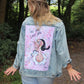 Back panel of light blue denim jacket featuring a vibrant artwork of Sailor Man’s lady, Olive Oyl, with a rough finish.