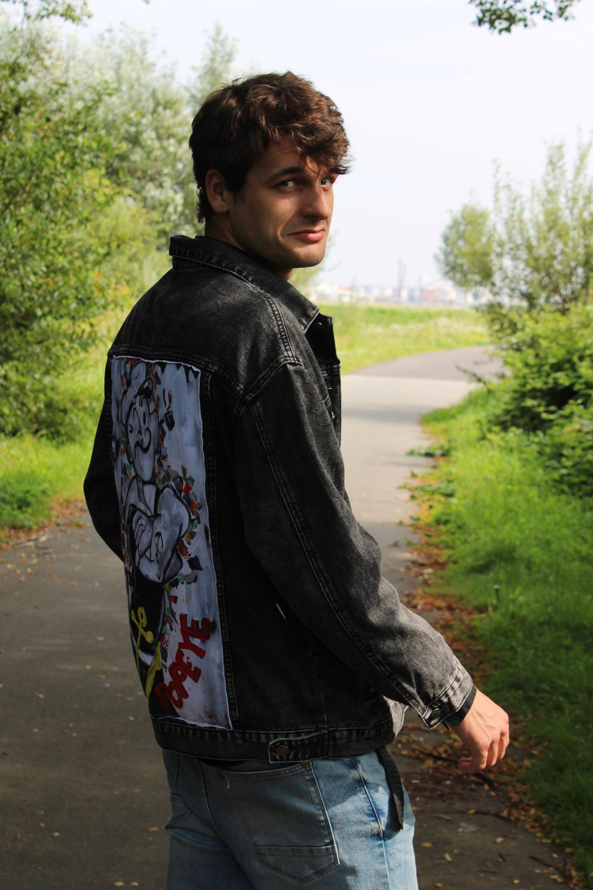 Unisex loose-fit black denim jacket with a rough-finished panel showcasing a Sailor Man design in a monochrome palette.