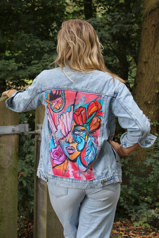 a light blue womens jacket with a striking pink, orange and redish color scheme panel on the back